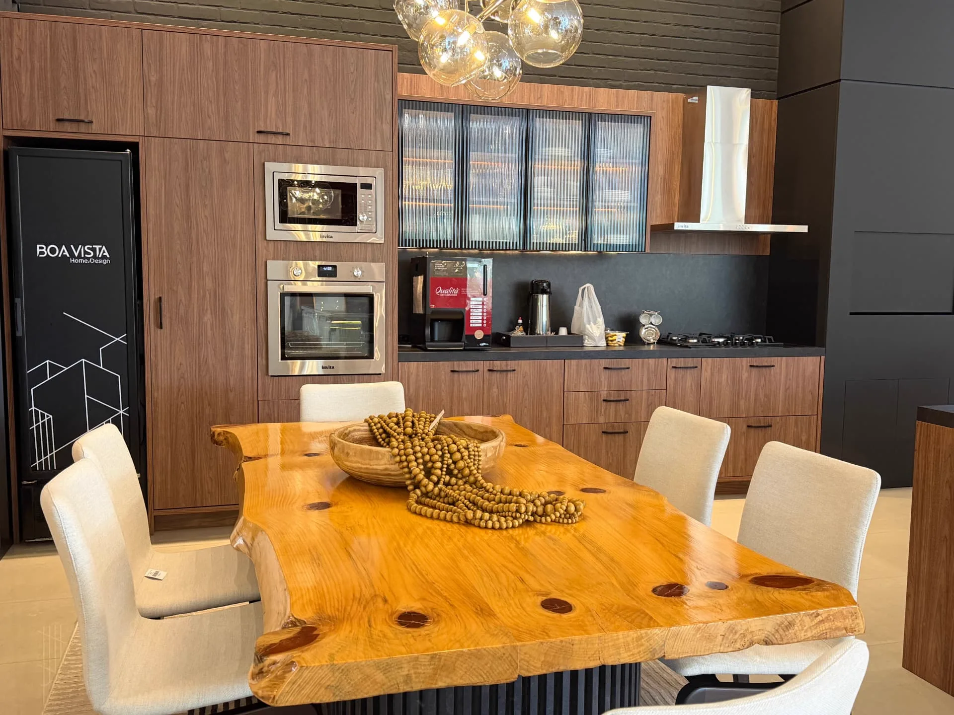 Cozinha do showroom com marcenaria em madeira e mesa de tronco maciço