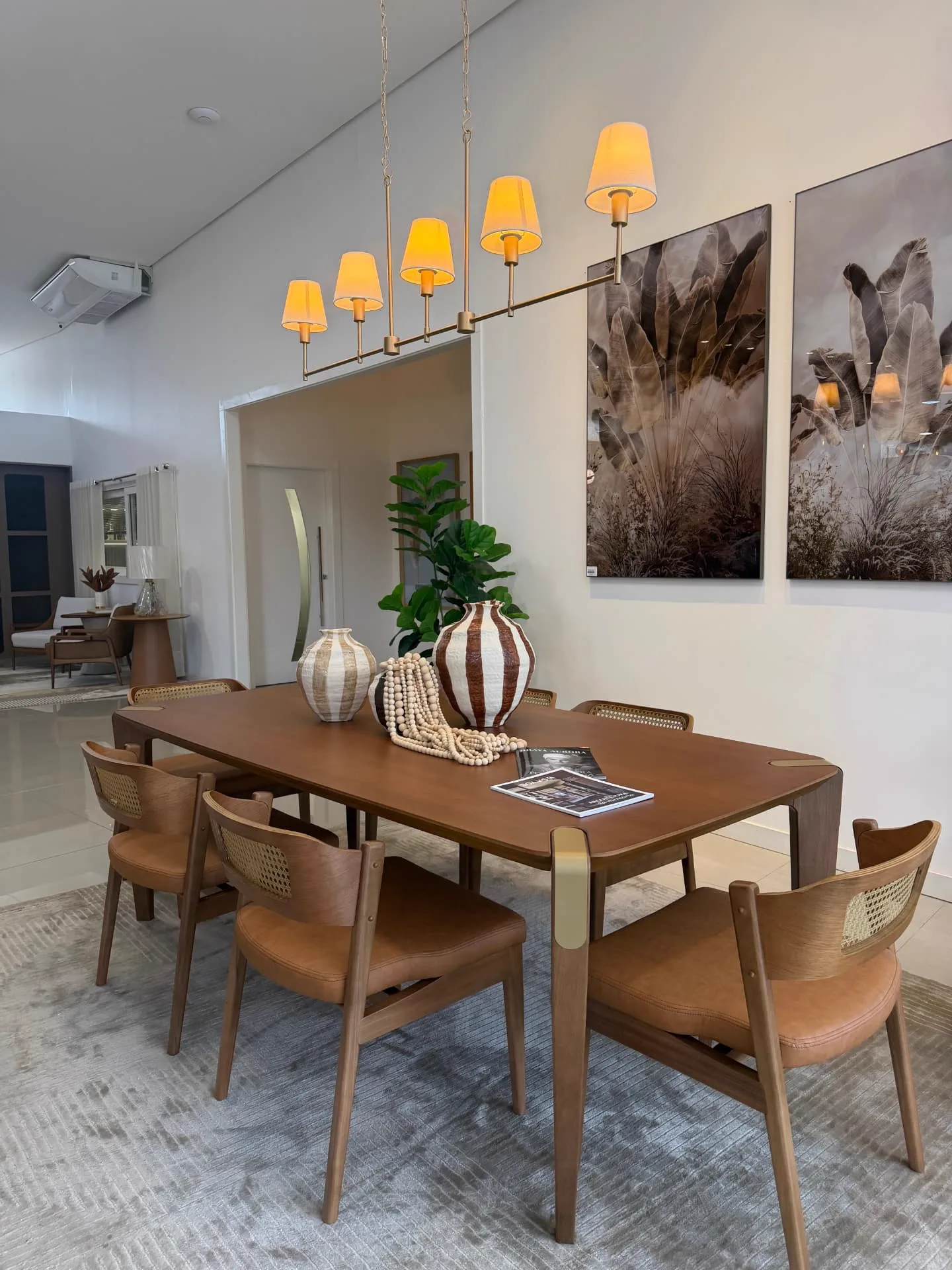 Sala de jantar montada no showroom com mesa em madeira e cadeiras de palhinha